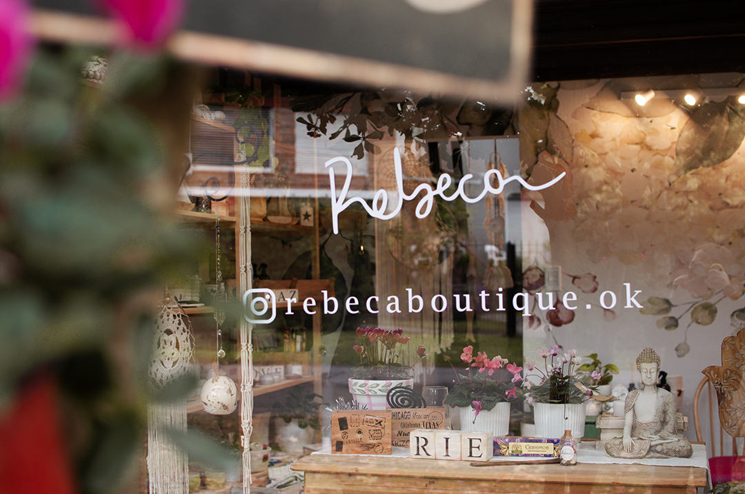 Vidriera original de Rebeca, con plantas, objetos y el nombre de la boutique